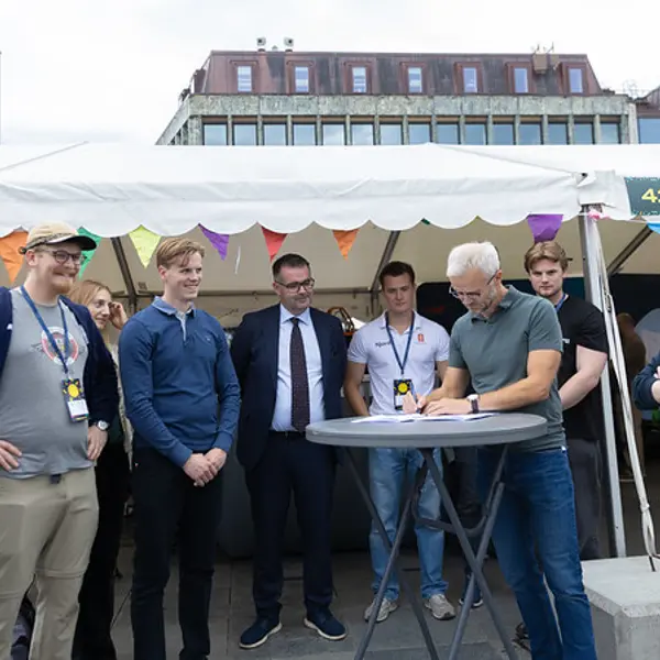 Daglig leder Erik Erlien signerer kontrakten omgitt av representanter fra studentorganisasjonene og ordfører Kent Ranum.
